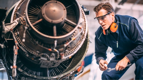 Image of an aviation engineer inspecting a disassembled jet engine.